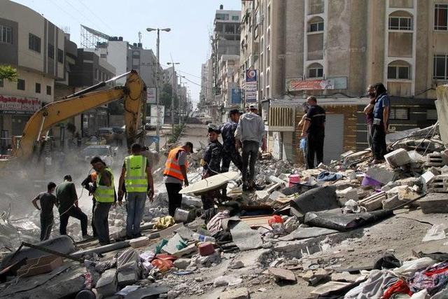△巴勒斯坦民防人员在加沙城被炸住宅楼的废墟中进行搜救