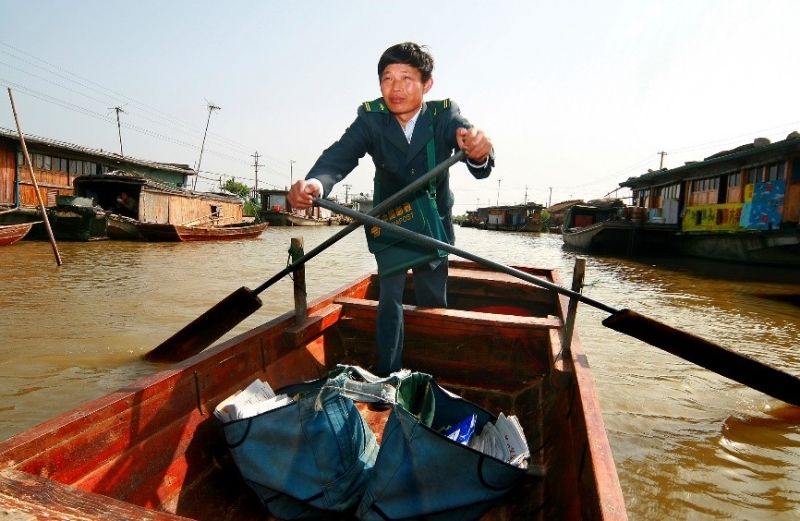 2013年，水上邮路投递员唐真亚划着小木船在湖区投递。刘春平摄