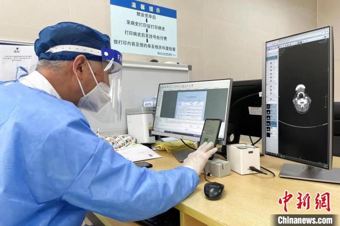 头颈部肿瘤多学科首席专家嵇庆海教授，仔细查阅互联网医院挂其专家号患者的一位病史和影像资料。　朱一齐 摄