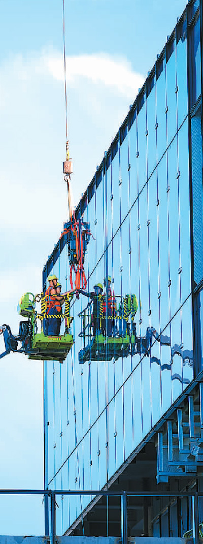 海口市江东新区一项目工地，神州工人在安装外墙玻璃。张 茂摄（人民图片）