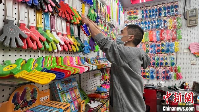 义乌国际商贸城一区，售卖玩具、助威道具等产品的店主潘祥明整理店铺的各色手拍器产品。　董易鑫 摄