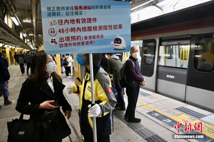 1月8日，香港与内地正式“通关”，大批旅客乘搭地铁从重开的落马洲站经口岸入境深圳。图为港铁职员于上水站提醒旅客入境内地的注意事项。 李志华 摄