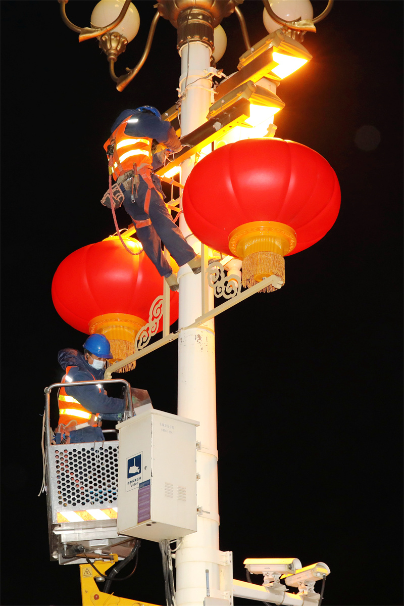 北京电力城市照明管理中心工作人员互相配合安装大红灯笼。张超摄