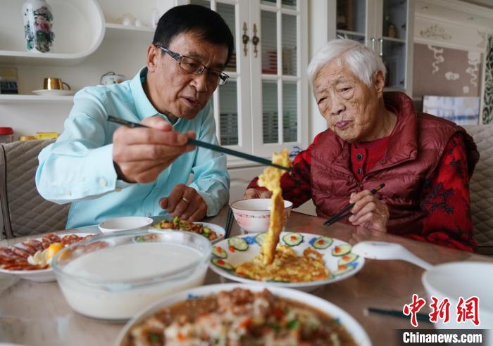 图为台商陈志明(左一)和母亲品尝台湾美食菜脯蛋。祖孙　马铭言 摄